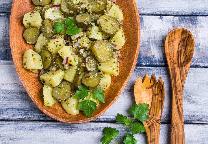 Homemade potato salad with pickles, onions, mustard seeds, and fresh parsley.