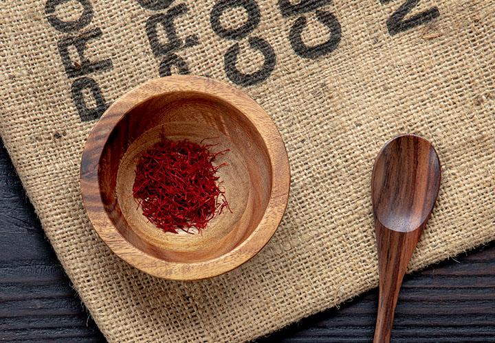 Premium Afghani saffron threads sitting in a wooden bowl ready for cooking.